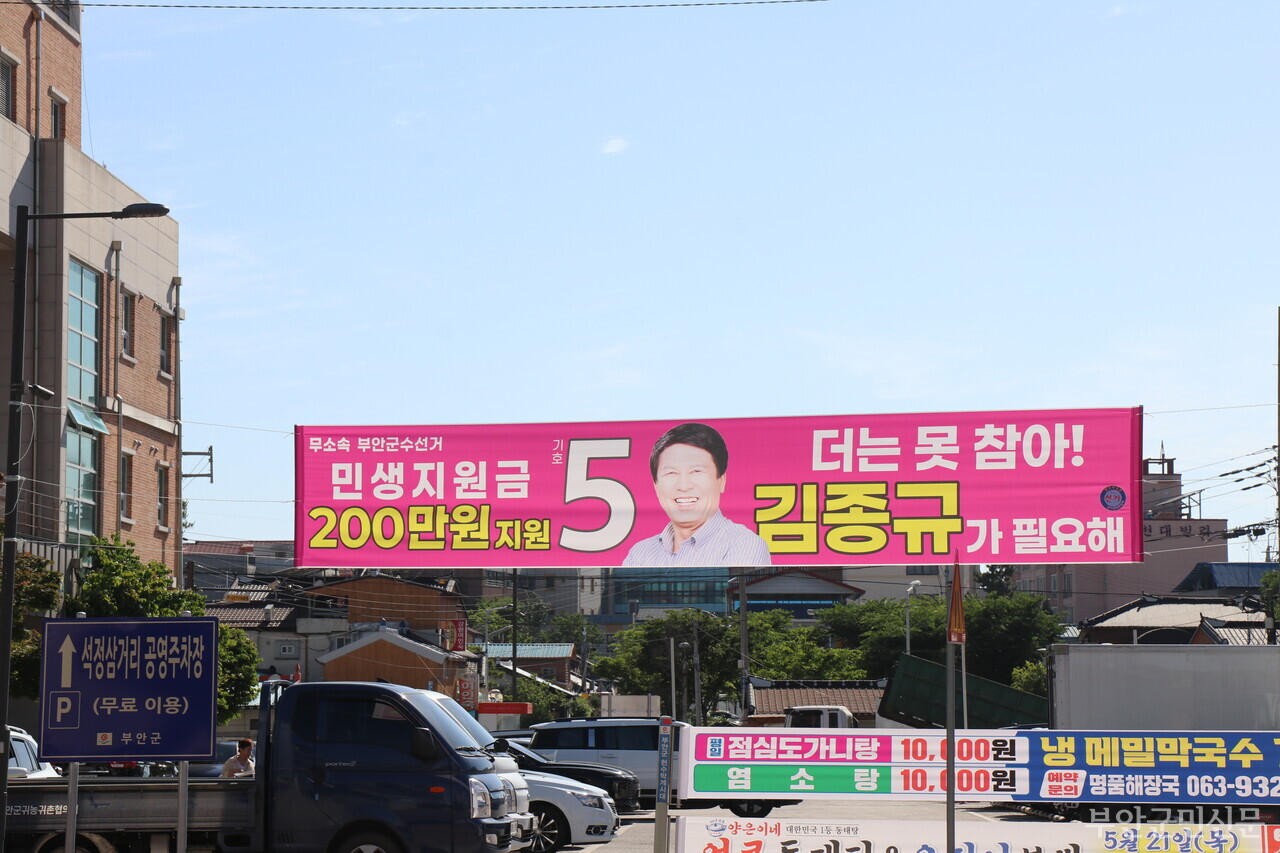 부안군수를 두 차례 역임한 무소속 김종규 후보는 부안읍 경제를 살리기 위한 해뜰마루 네이처파크 조성을 제1 공약으로 내걸었다. 300억 원~500억 원의 예산이 투입되는 이 사업은 연간 약 4백만 명이 탐방하는 순천만과 비교되는 국가정원 조성사업으로 부안읍을 관광 중심지로 격상시키고 부안군 생활인구(관광객) 급증과 소상공인 매출 확대, 생태 중심 관광 부안의 이미지 제고 등의 효과를 기대할 수 있다. 사진은 지난 5월 6일 전북특별자치도의회 브리핑룸에서 “돈 버는 일등 행정, 군민이 잘사는 부안을 만들겠다”며 부안군수 출마를 공식 선언하는 모습과 부안읍사무소 옆에 게시된 현수막.